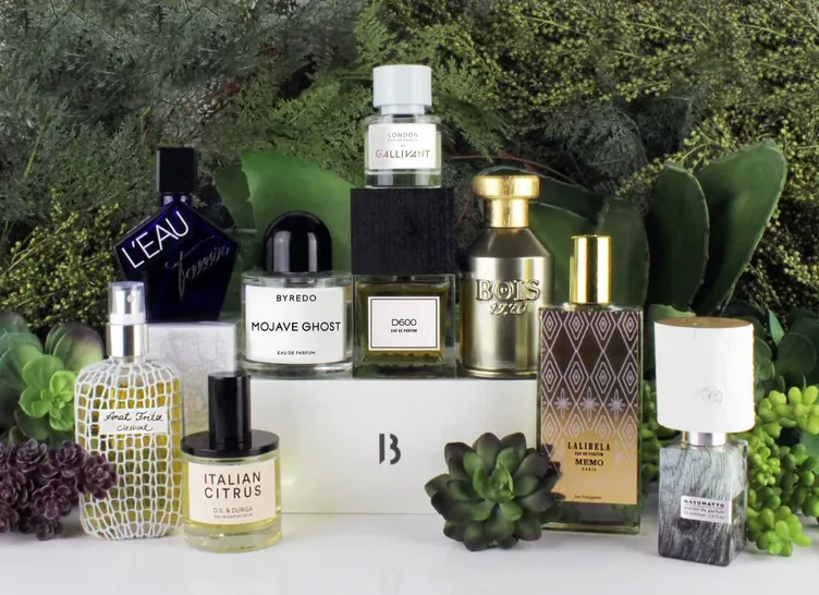 Sélection de flacons de parfum de niche devant un mur végétal
